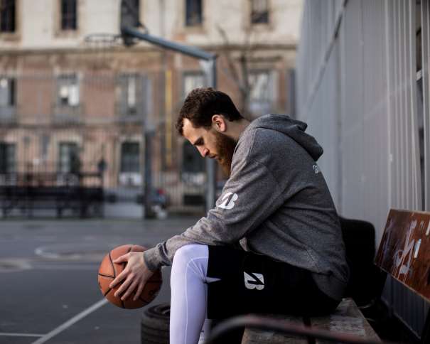 En esta foto podemos ver a Sergio Rodríguez ("Chacho"), Jugador de los Philadelphia 76ers de la NBA, con el balón entre sus manos, sentado en un banco, en una pista exterior