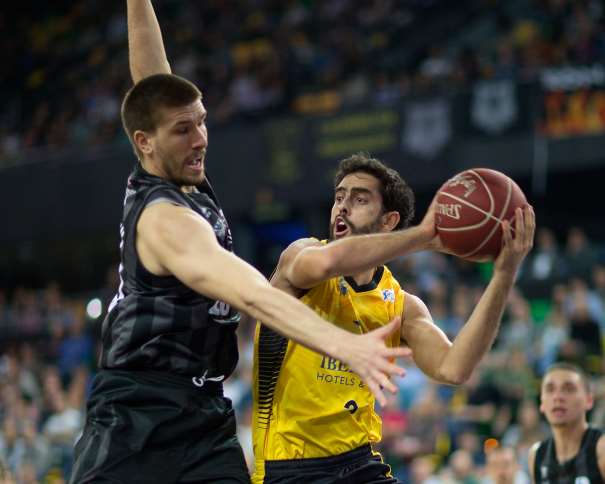 En esta foto podemos ver cómo Javi Beirán busca poder dar un pase ante la oposición de un defensordel Bilbao en el Partido de la Sexta Jornada de la Liga ACB 2016-2017, en el que consiguieron una nueva Victoria