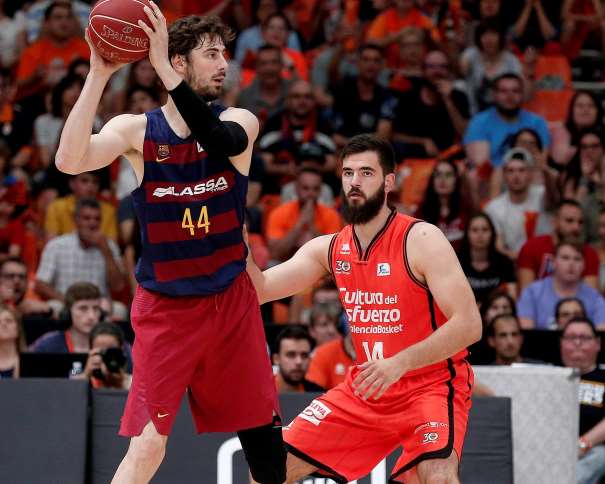En esta foto, facilitada por la Liga ACB de Baloncesto, podemos ver al jugador croata del Barcelona Ante Tómitch con el balón por encima de la cabeza, alejándolo de su defensor